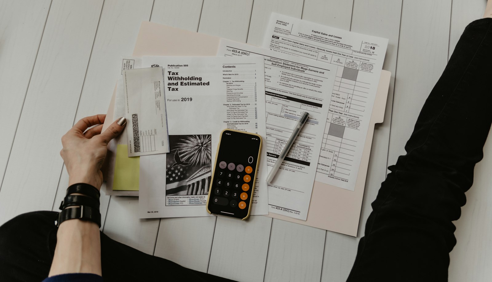 Persona revisando documentación financiera con una calculadora sobre la mesa